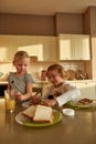 Cute brother spreading chocolate nut butter on toasted bread while preparing breakfast for his little sister and himself Royalty Free Stock Photo