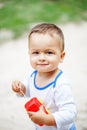 Cute brown-eyed little boy playing with a red plastic toy car Royalty Free Stock Photo