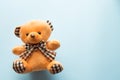 Cute brown teddy bear child toy with visible upper body and open arms on blue background with copy space