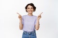 Cute brunette girl in casual outfit pointing fingers sideways, left and right empty spaces, two variants, sales Royalty Free Stock Photo