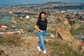 A cute brunette girl enjoys the stunning scenery of Tbilisi from the hill. The whole city at her feet