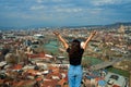 A cute brunette girl enjoys the stunning scenery of Tbilisi from the hill. The whole city at her feet