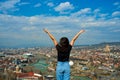 A cute brunette girl enjoys the stunning scenery of Tbilisi from the hill. The whole city at her feet