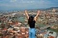 A cute brunette girl enjoys the stunning scenery of Tbilisi from the hill. The whole city at her feet