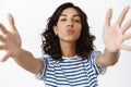 Cute brunette girl kissing you and reaching for hug, looking flirty at camera, pucker lips for kiss, standing in t-shirt Royalty Free Stock Photo