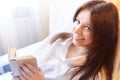 Cute brunette girl is reading small book of poetry in bedroom in morning. Young pregnant woman in the maternity hospital Royalty Free Stock Photo