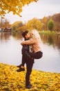 Cute brunette guy holds in his arms and kisses a beautiful blonde girl. Loving teens are happy, smiling, kissing. Concept of