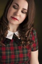 Cute brunette in tartan dress with red lips and curles. Studio portrait