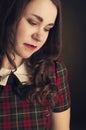 Cute brunette in tartan dress with red lips and curles. Studio portrait