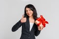 Cute brunette teenager girl in black blazer celebrating birthday, holding gift box and showing thumb up, says: i like it, grey