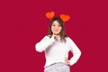 Cute brunette with two red handmade hearts in her hair, flirt on a red background. Empty side space Royalty Free Stock Photo