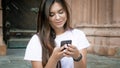 Portrait of cute brunette woman sitting on stone stairs and typing message on mobile phone Royalty Free Stock Photo