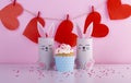 Cute bunnies made of paper and red hearts on the background