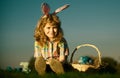 Cute bunny child boy with rabbit ears. Children hunting easter eggs on sky background with copy space. Child with easter
