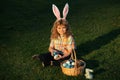 Cute bunny child with rabbit ears. Child boy hunting easter eggs in spring lawn laying on grass.