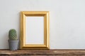 Cute cactus pot and empty golden vintage photo frame on old wooden table over white wall background copy space. Creative idea Royalty Free Stock Photo