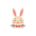 A cute cartoon bunny in a red bow tie is looking out of the hole and smiling. Isolated on white background. Royalty Free Stock Photo