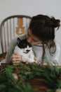Cute cat helping woman making rustic christmas wreath. Authentic home moments, pet and holidays