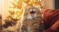 Cute cat lying on modern armchair and yawning on background of stylish decorated christmas tree in sunny room. Pet and winter