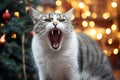 Cute cat yawning in front of christmas tree with lights