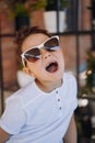 Cute cauasian boy in white tee shirt and sunglasses posing for camera and showing his lost tooth. Royalty Free Stock Photo