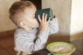 Cute caucasian baby boy with blond hairs drinking milk and eating porridge. Royalty Free Stock Photo