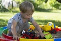 Cute Caucasian baby boy playing with the sand and toys in sandbox