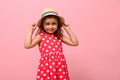 Cute Caucasian baby girl in pink summer dress and straw hat posing over pink wall background with copy space. Studio portrait of Royalty Free Stock Photo