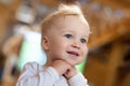 Cute caucasian blond toddler boy pleasantly surprised looking somewhere indoors. Adorable little child holding hands under chin Royalty Free Stock Photo