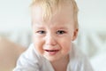 Cute caucasian blond toddler boy portrait crying at home during hysterics. Little child feeling sad. Little actor acting sadness