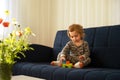 Cute caucasian blonde baby girl,toddler, infant, adorable kid 1,2 years old lying on sofa playing with tinker toys in