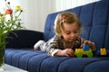 Cute caucasian blonde baby girl,toddler, infant, adorable kid 1,2 years old lying on sofa playing with tinker toys in