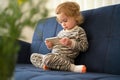 Cute caucasian blonde baby girl,toddler, infant, adorable kid 1,2 years old lying on sofa using mobile phone,technology