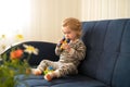 Cute caucasian blonde baby girl,toddler, infant, adorable kid 1,2 years old on sofa biting tinker toy in modern cozy