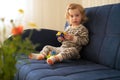 Cute caucasian blonde baby girl,toddler,infant,adorable kid 1,2 years old on sofa playing with tinker toy in cozy