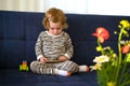 Cute caucasian blonde baby girl,toddler, infant, adorable kid 1,2 years old on sofa using mobile phone,technology in