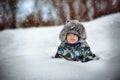 cute caucasian boy in warm winther jacker with fur hoody laying in snow in countryside on winter day Royalty Free Stock Photo