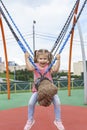 Cute caucasian child girl swinging on a swing on a children`s playground