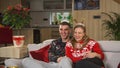 Cute Caucasian couple watching television on Christmas day in holiday sweaters Royalty Free Stock Photo