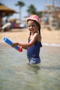 Cute caucasian four year old girl in swimsuit playing with a toy pump in the sea interior Royalty Free Stock Photo