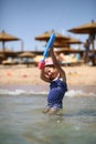 Cute caucasian four year old girl in swimsuit playing with a toy pump in the sea interior Royalty Free Stock Photo