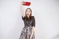 Cute caucasian friendly girl stands with a mobile phone in her hand and takes a happy emotional selfie on a white background in th Royalty Free Stock Photo