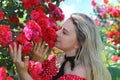 Cute Caucasian girl in a red dress with polka dots enjoying the scent of roses Royalty Free Stock Photo