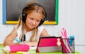 Cute caucasian girl smiling and watching at the tablet at home schooling. Distance education and learning concept