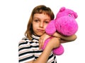 A cute Caucasian girl of 7 years old with blond hair cuddles and hugs a pink hippopotamus. Hippo plush toy. An expression of love, Royalty Free Stock Photo