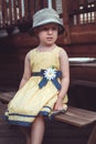 cute Caucasian girl in yellow dress and hat outside on house backyard on summer day Royalty Free Stock Photo