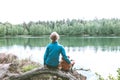 Cute Caucasian little girl on the lake with her plush toys, teddy bear and bunny. Back view Royalty Free Stock Photo