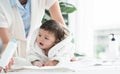 Cute Caucasian little toddler baby girl wear bathrobe after bathing is smiling and lying while mother apply  talcum powder on her Royalty Free Stock Photo