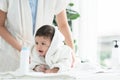 Cute Caucasian little toddler baby girl wear bathrobe after bathing is smiling and lying on towel while mother wipe her dry Royalty Free Stock Photo