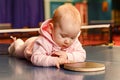 Caucasian six-month-old baby in a pink suit is lying on her stomach on a tennis table. little girl holding a table tennis racket Royalty Free Stock Photo